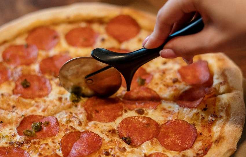 pizza die wordt gesneden met een pizzasnijder